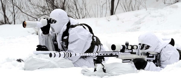 Bild av en Airsoft sniper och en spotter ute i vinterlandskap, i vit kamouflage.